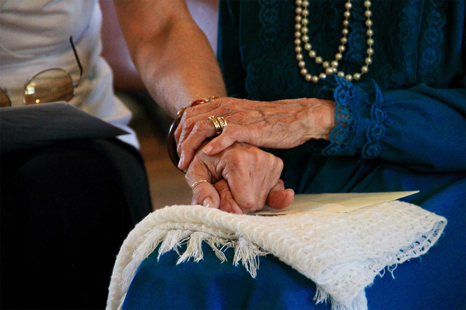 Closeup of two people holding hands.