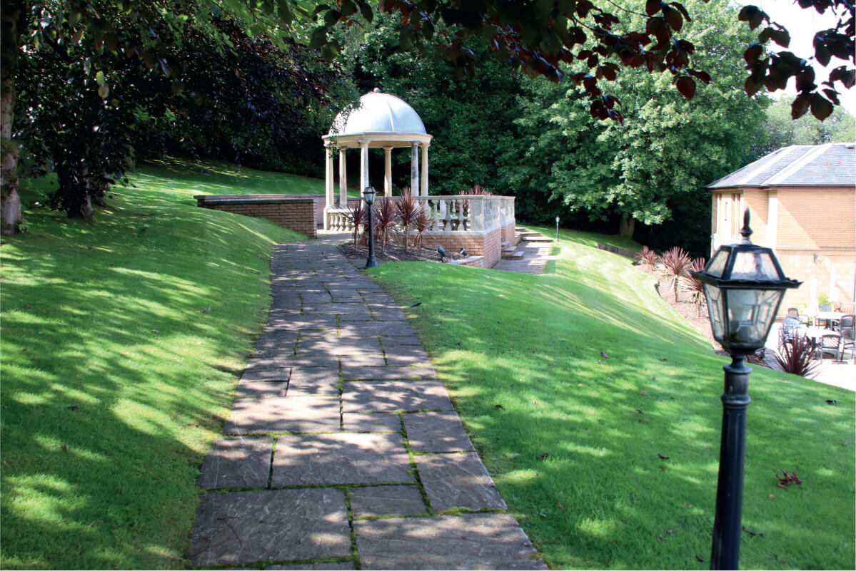 Grassy hill with a path leading to a seating area.