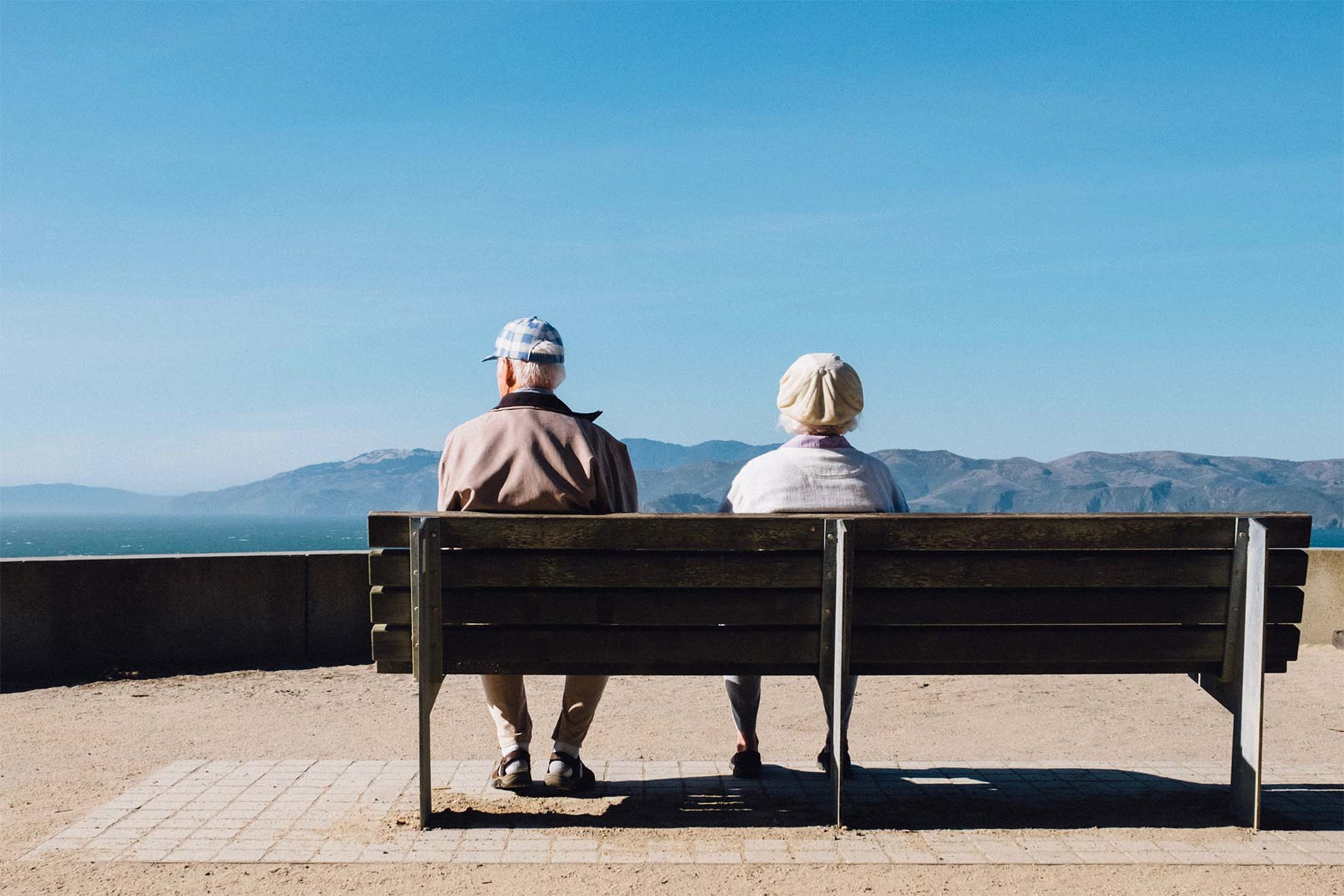 Two care home residents sitting on a bench looking at a beautiful view.