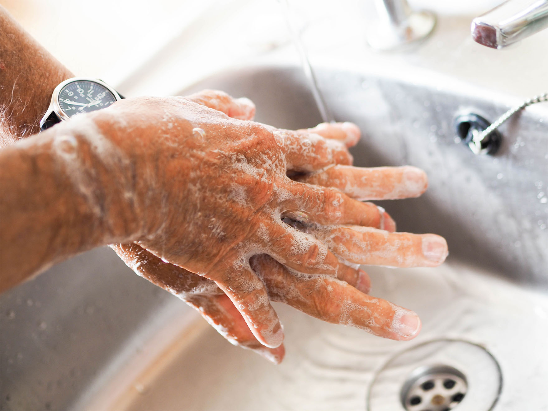 Closeup of someone throughly washing their hands with lots of soap bubbles.