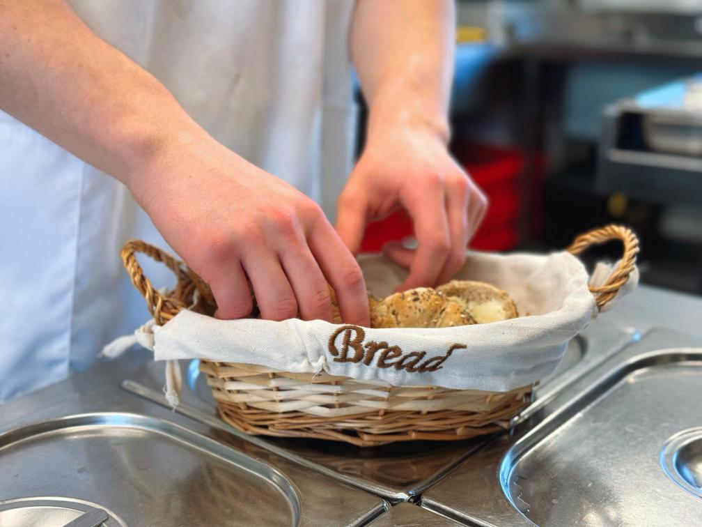 Bread being arranged in a container ready for dinner.