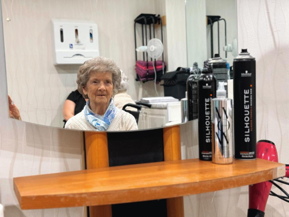 Lady sat in front of mirror ready to have her hair done at the salon.