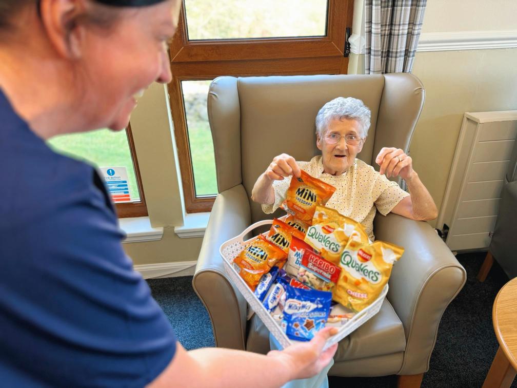 Resident of the care home selecting a snack from the snack basket.