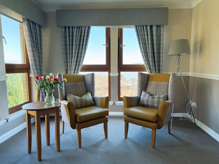 Two comfortable chairs positioned in front of a sunny bay window.